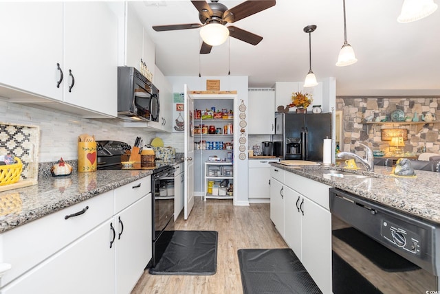 kitchen with a sink, light wood-type flooring, black appliances, white cabinetry, and backsplash