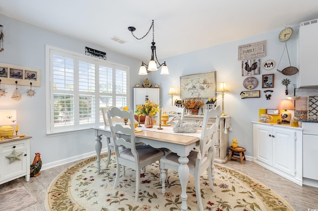 dining area with a chandelier, light wood finished floors, visible vents, and baseboards