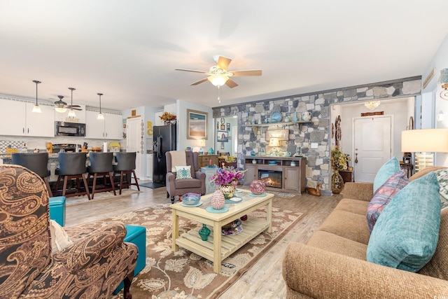 living room featuring light wood-style floors, ceiling fan, and a fireplace