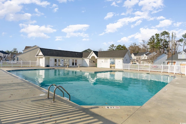 community pool featuring a patio area, a residential view, and fence