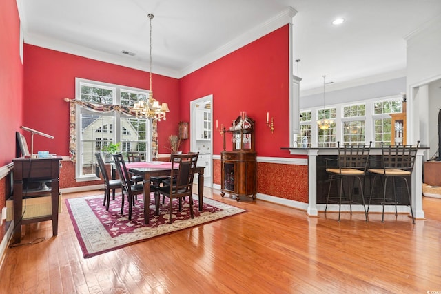 dining room featuring a chandelier, ornamental molding, hardwood / wood-style flooring, and baseboards