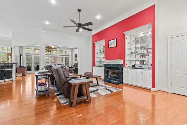 living room featuring light wood-type flooring, a high end fireplace, and ornamental molding