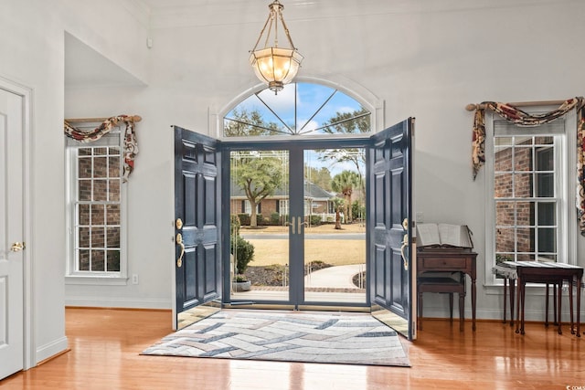 foyer entrance featuring a chandelier, french doors, baseboards, and wood finished floors