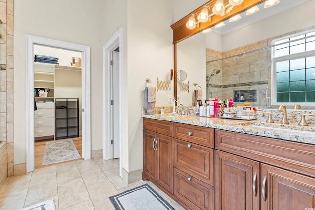 full bath with double vanity, a spacious closet, a stall shower, a sink, and tile patterned flooring