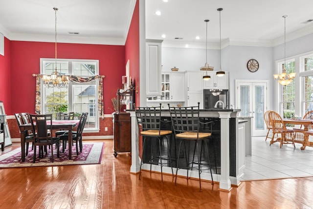 kitchen featuring light wood-style flooring, crown molding, french doors, fridge, and a chandelier