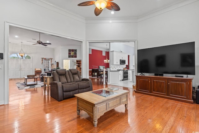 living room with ornamental molding, light wood-style flooring, and a ceiling fan