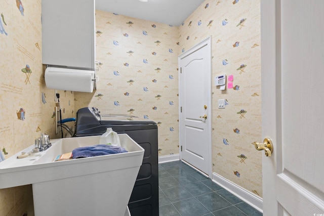 clothes washing area featuring a sink, dark tile patterned flooring, laundry area, baseboards, and wallpapered walls