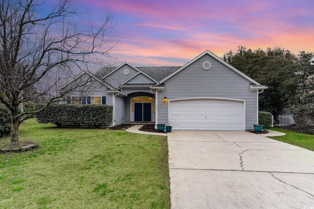 view of front of property featuring concrete driveway, a lawn, and an attached garage