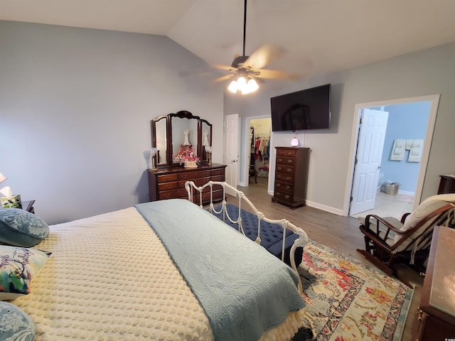 bedroom featuring dark wood finished floors, baseboards, vaulted ceiling, a closet, and a walk in closet