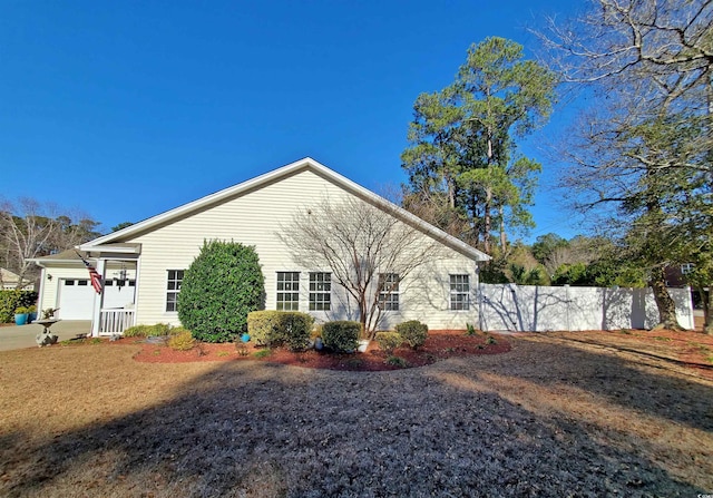 view of side of property featuring fence, driveway, and an attached garage