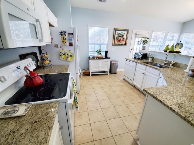 kitchen featuring light tile patterned floors, a healthy amount of sunlight, white cabinets, a sink, and white appliances