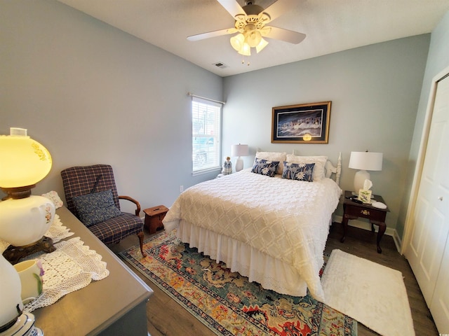 bedroom featuring baseboards, dark wood finished floors, visible vents, and a ceiling fan