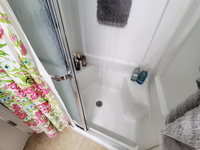 bathroom with a stall shower and tile patterned flooring