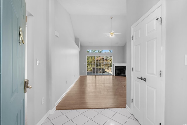 hall with lofted ceiling, light tile patterned flooring, and baseboards