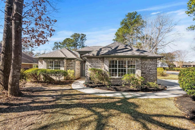 view of front of house with brick siding, a front yard, and a shingled roof