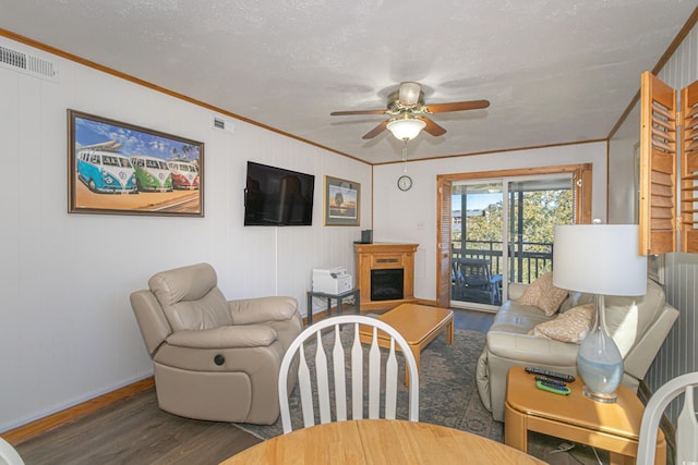 living room with visible vents, a ceiling fan, dark wood-type flooring, crown molding, and a fireplace