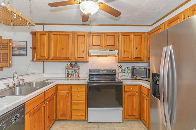 kitchen with tile countertops, under cabinet range hood, a sink, appliances with stainless steel finishes, and brown cabinetry