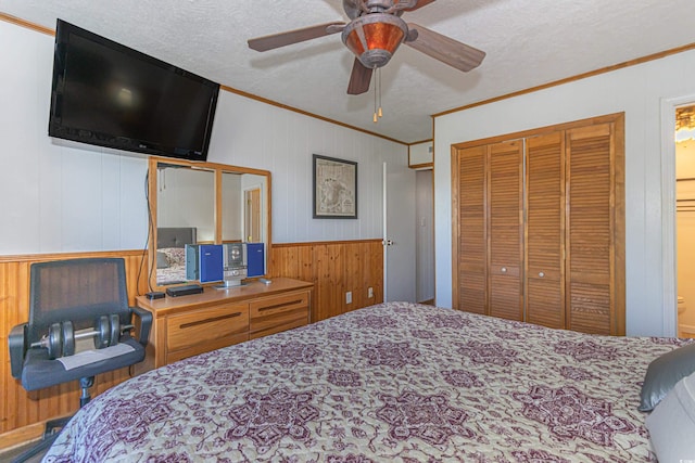 bedroom with a textured ceiling, a closet, a ceiling fan, and crown molding