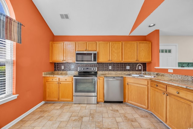 kitchen with lofted ceiling, a sink, visible vents, appliances with stainless steel finishes, and backsplash