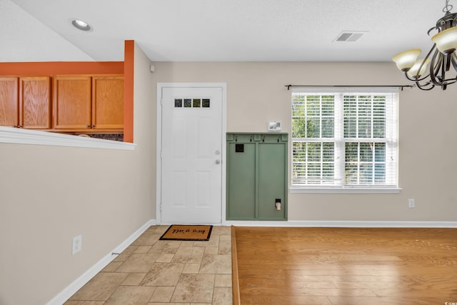 foyer entrance with a textured ceiling, a notable chandelier, recessed lighting, visible vents, and baseboards