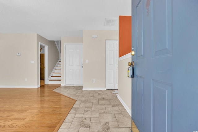 foyer with baseboards, visible vents, light wood finished floors, and stairs