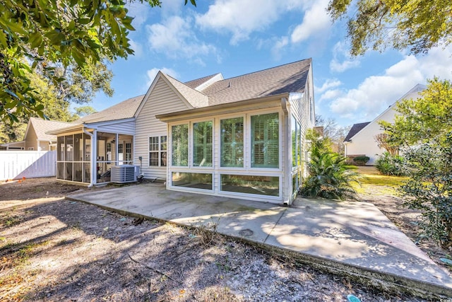 rear view of property with a shingled roof, a patio, a sunroom, fence, and central AC