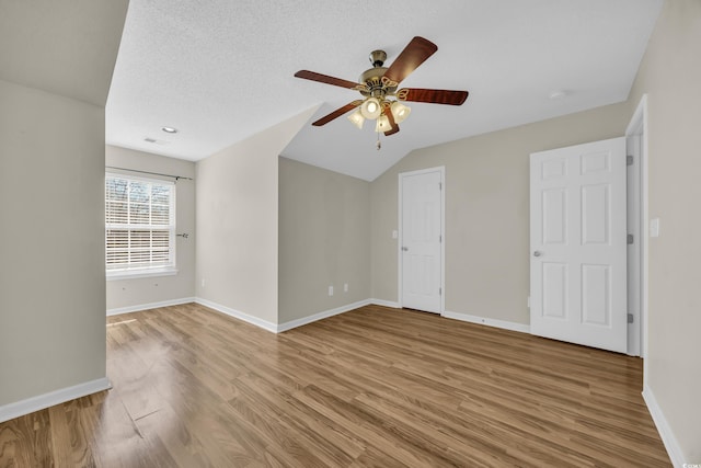 unfurnished room featuring light wood finished floors, visible vents, ceiling fan, a textured ceiling, and baseboards