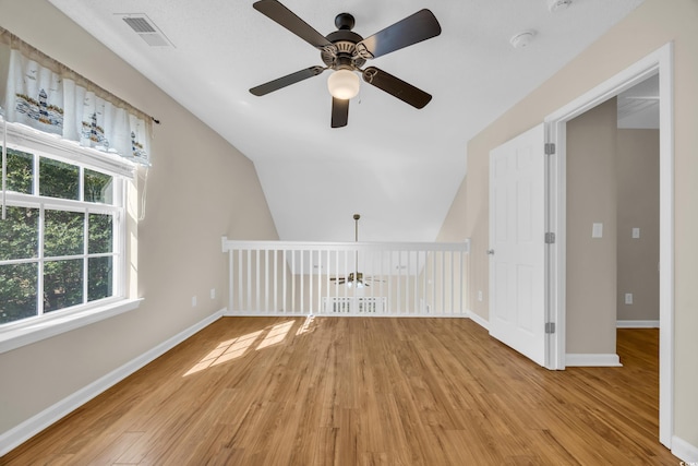 additional living space featuring lofted ceiling, light wood-style flooring, visible vents, and baseboards