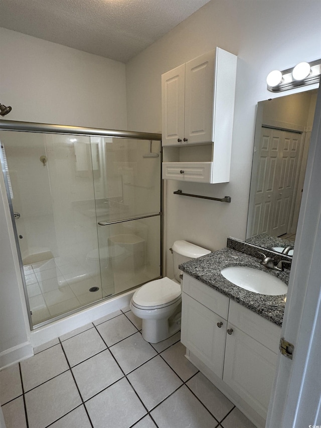 full bathroom featuring a textured ceiling, a stall shower, toilet, and tile patterned floors