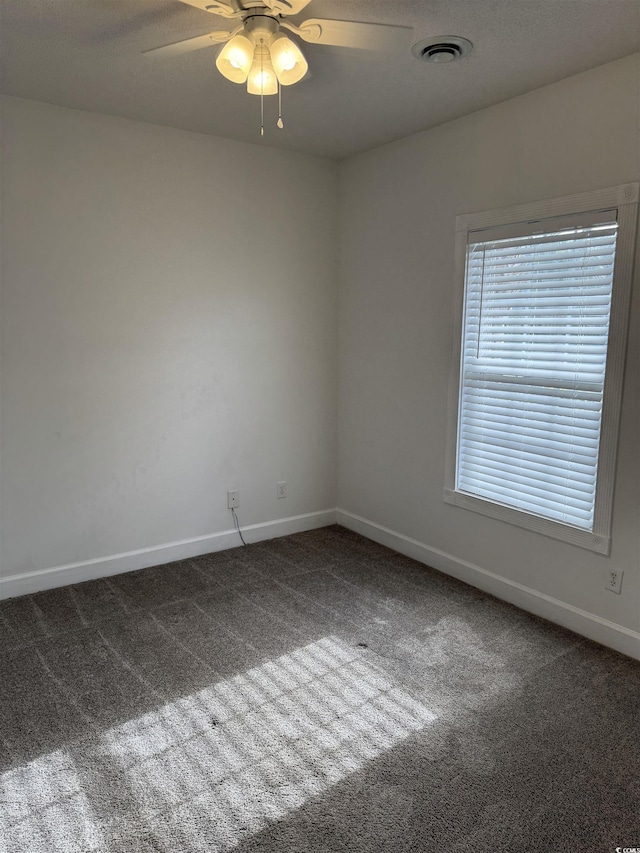 empty room featuring a ceiling fan, carpet, visible vents, and baseboards