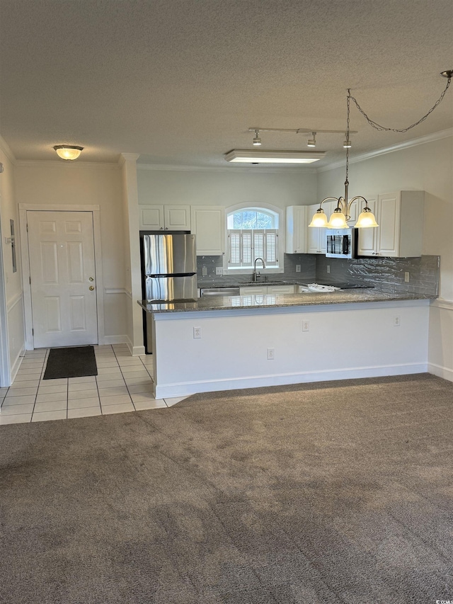 kitchen featuring a chandelier, stainless steel appliances, a peninsula, white cabinets, and decorative light fixtures