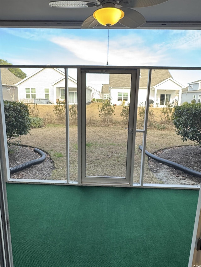 sunroom / solarium with ceiling fan and a residential view