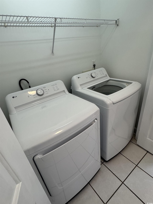 washroom featuring light tile patterned floors, laundry area, and washing machine and clothes dryer