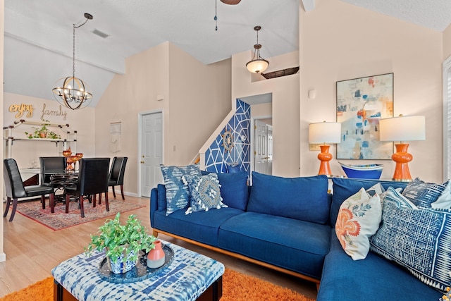 living area with visible vents, stairway, wood finished floors, beamed ceiling, and a chandelier