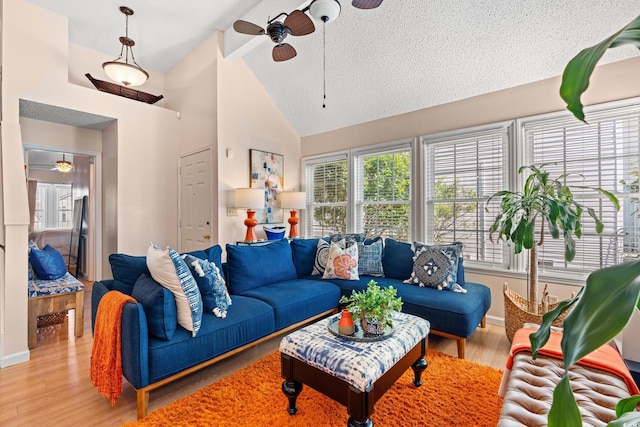 living room with ceiling fan, high vaulted ceiling, a textured ceiling, baseboards, and light wood finished floors