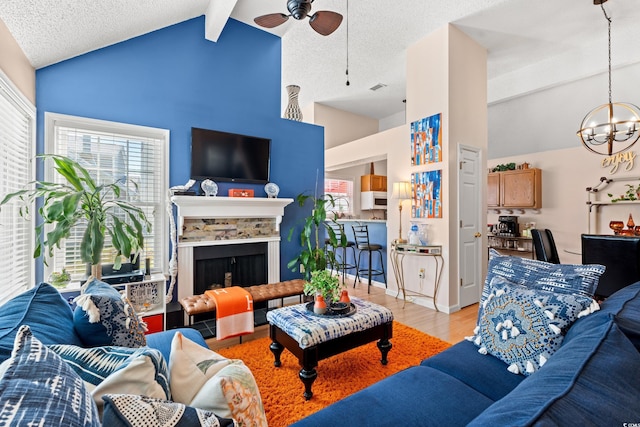 living room with a fireplace with raised hearth, a textured ceiling, visible vents, light wood-style floors, and beamed ceiling