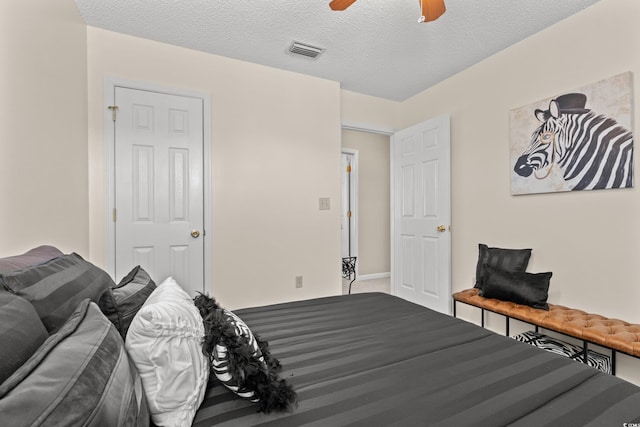 bedroom featuring a textured ceiling, carpet floors, visible vents, and a ceiling fan