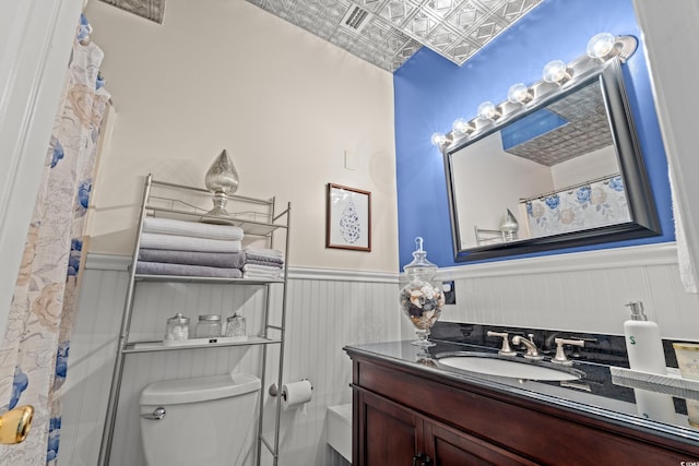 full bathroom with toilet, a wainscoted wall, an ornate ceiling, and vanity