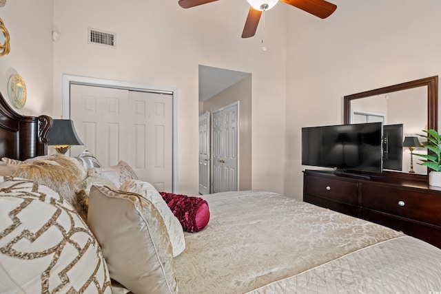 bedroom with ceiling fan, a high ceiling, and visible vents