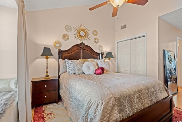 bedroom featuring light wood finished floors, visible vents, a ceiling fan, high vaulted ceiling, and a closet