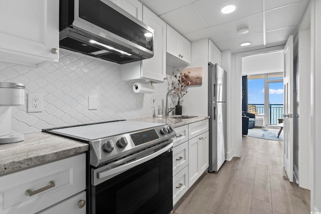 kitchen with white cabinetry, appliances with stainless steel finishes, light stone counters, and a sink