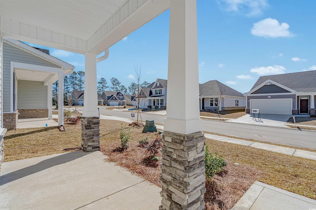 view of patio / terrace with driveway, a residential view, and a porch