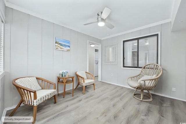 sitting room featuring light wood-type flooring, ceiling fan, and crown molding