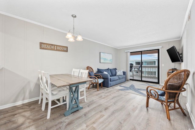 dining area with light wood-type flooring, an inviting chandelier, and ornamental molding