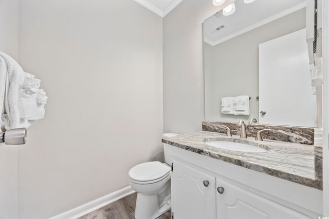 half bath featuring toilet, wood finished floors, vanity, baseboards, and crown molding