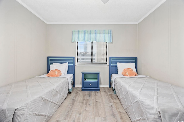 bedroom featuring light wood finished floors, ornamental molding, and a decorative wall