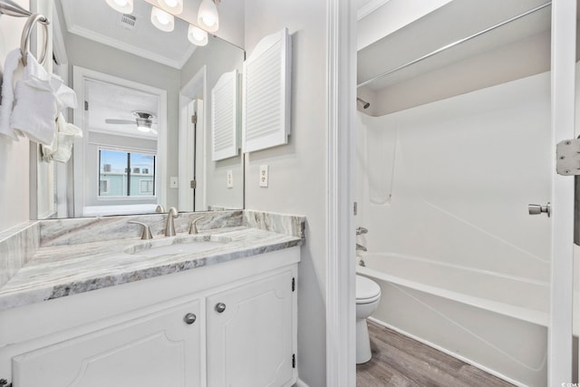 bathroom featuring toilet, wood finished floors, vanity, ornamental molding, and washtub / shower combination