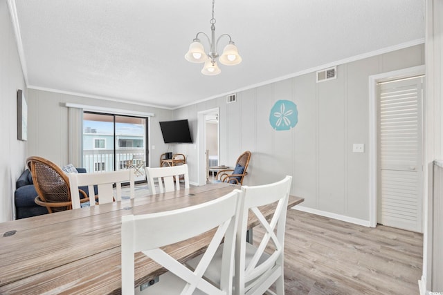 900 N Waccamaw Dr Unit 303, Murrells Inlet, SC 29576 - dining space featuring a chandelier, ornamental molding, light wood-style floors, a decorative wall, and a textured ceiling