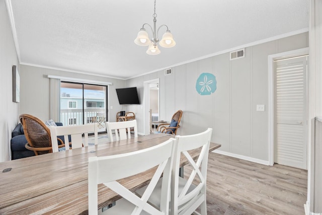 dining space featuring a chandelier, light wood-style floors, visible vents, and crown molding