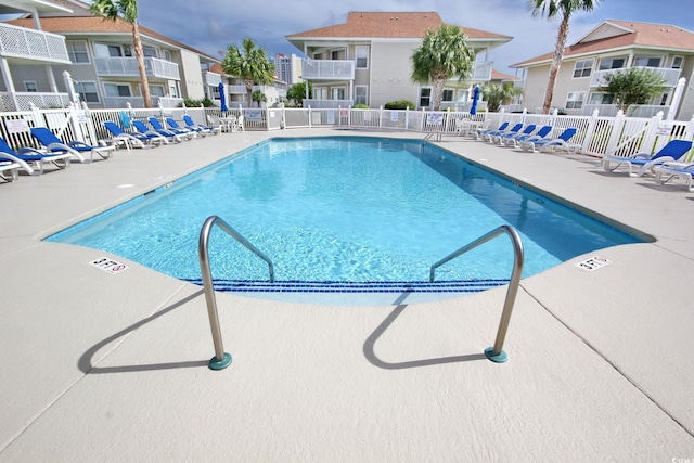 pool with a patio area and fence